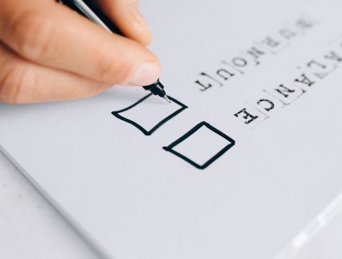 A hand drawing checkboxes on a checklist, themed around balance and burnout.